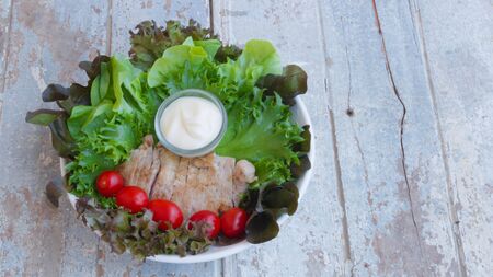 healthy pork steak served with tomatoes and fresh salad vegetables on an old wooden boardの写真素材