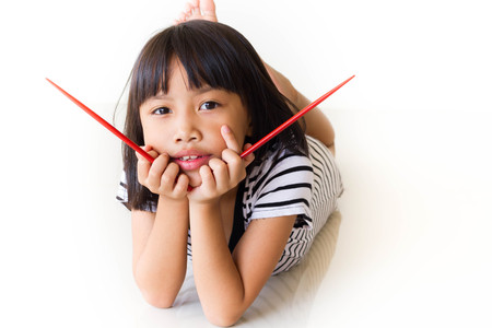 Joyful children girl with red chopsticks sitting at the tableの写真素材