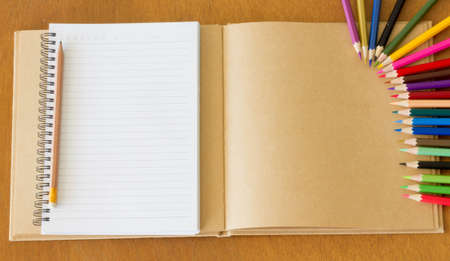 Blank notebook and colorful pencils on the wooden table. View from aboveの写真素材