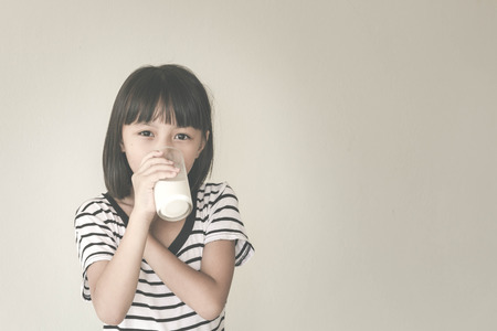 Gorgeous little girl wearing striped encouraged to drink milk - Vintage Filter Effectの写真素材
