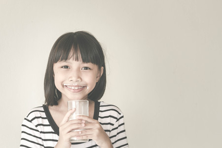 Gorgeous little girl wearing striped encouraged to drink milk - Vintage Filter Effectの写真素材