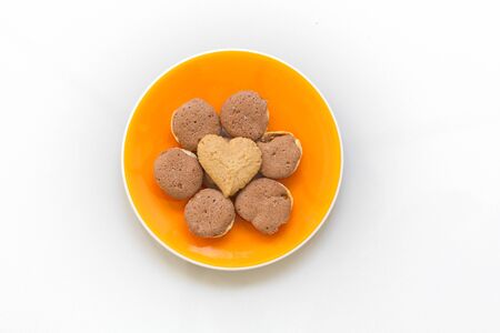 Chocolate cookies and butter cookies heart shape on orange dish on white backgroundの写真素材