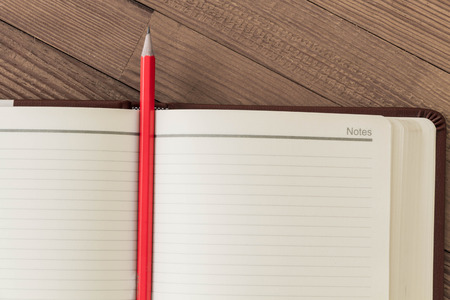 Note blank open book with orange pencil on textured wood backgroundの写真素材