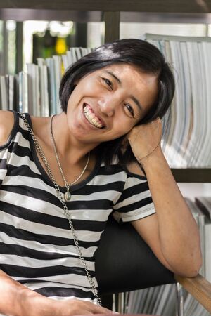 Asian woman in white and black shirts smiling stay in the cafeの写真素材