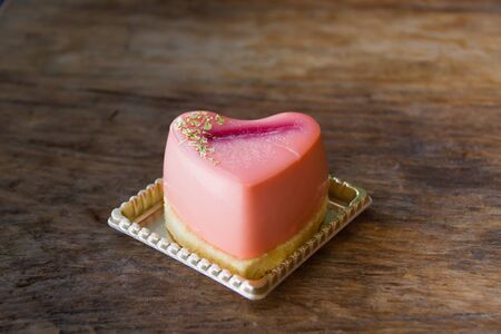 Heart shaped rose mousse cake on wooden tableの写真素材