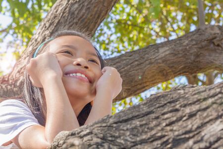 Close up happy adorable asian children climbing trees with sun flare.の写真素材