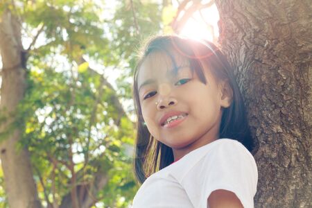 Close up happy adorable asian children climbing trees with sun flare.の写真素材