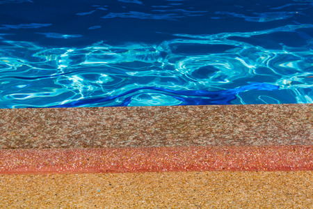 Stone floor with rippled pattern of clean water in a blue swimming poolの写真素材