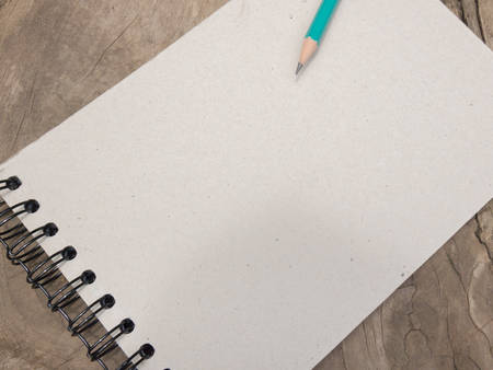 Blank paper and green pencil on the wooden table. View from above