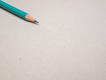Blank paper and green pencil on the wooden table. View from above