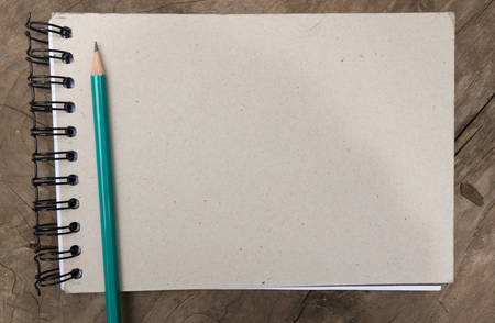 Blank paper and green pencil on the wooden table. View from above