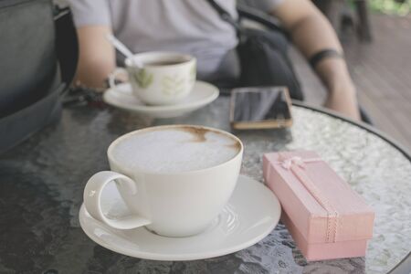 Selective focus white cup of Coffee, latte on the wooden table with pink gift.の写真素材
