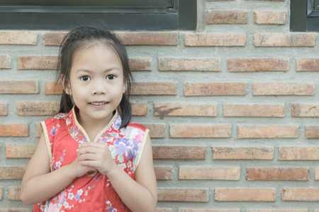 Adorable asian kid wear chinese red dress in coffee shopの写真素材