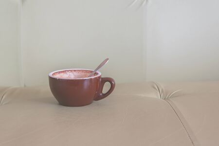 Brown cup of coffee on soft green sofa in the coffee shop. Coffee cup relaxation concept.の写真素材