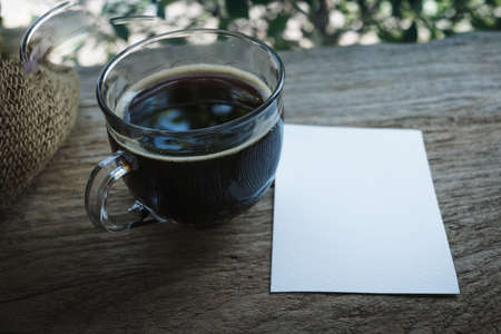 Cup of coffee with blank white paper for copy space in coffee shop.