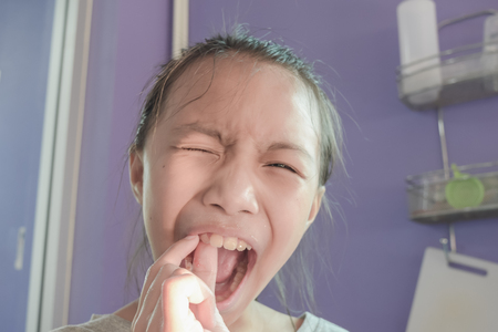 Little asian girl is toothache then her trying extracted from herself mouths. Concept healthcare.の写真素材