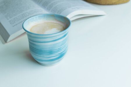 Blue coffee cup on the desk with books. Concept coffee lover background.の写真素材