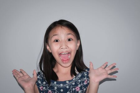 Selective focus beautiful little girl surprise to something on gray background. Concept kid confidence.の写真素材