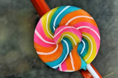Colorful candies in vase on table on wooden backgroundの写真素材
