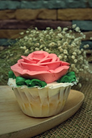 pink rose cupcake on wooden platesの写真素材