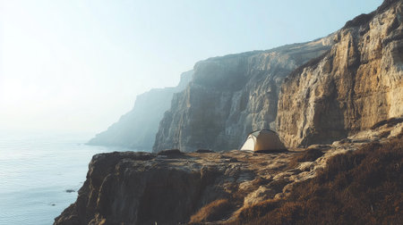 A minimalist camping tent on a rocky terrain, overlooking a breathtaking cliffside view.の素材