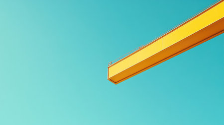 Minimalistic shot of a yellow crane's boom cutting through a clear blue sky, a stark contrast of engineering and natureの素材