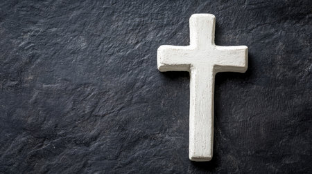Simple white cross on a dark background, ample room for text focused on inner peaceの素材