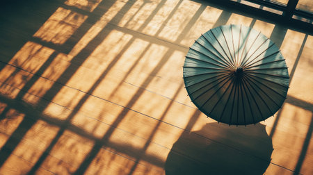 A serene image featuring an elegant umbrella casting beautiful shadows on a wooden floor, illuminated by warm sunlight, creating a tranquil atmosphere with intricate patterns.の素材