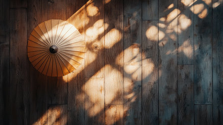 A beautiful Japanese umbrella rests on rustic wooden flooring, creating intricate shadows in soft natural light. This scene evokes tranquility and aesthetic elegance, perfect for serene moments.の素材