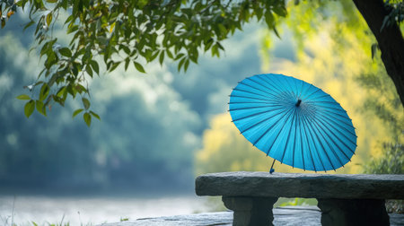 A serene landscape featuring a vibrant turquoise umbrella on a stone bench, framed by lush greenery and calm water, creating an inviting atmosphere for relaxation.の素材