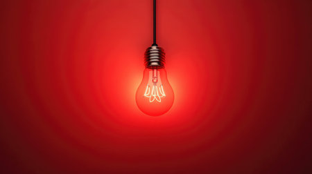 A striking red light bulb hangs in a minimalist setting, emitting a warm glow against a smooth red background, creating a captivating and cozy atmosphere.の素材