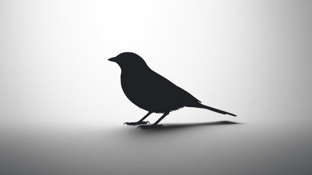 A lone bird in black silhouette, sitting still against a clean white backdrop, creating a simple yet impactful visual.の素材