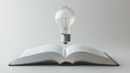 Open book with a bright, floating light bulb, representing innovation in education and technology on a minimalist white background.の素材