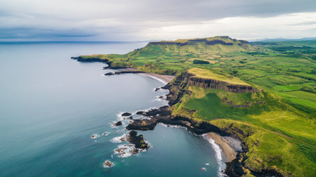 Aerial view of the coastline surrounding the Giant's Causeway, with lush green hills meeting the dramatic basalt rock formations. No people included.の素材