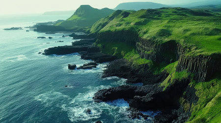 Aerial view of the coastline surrounding the Giant's Causeway, with lush green hills meeting the dramatic basalt rock formations. No people included.の素材
