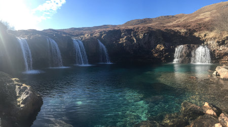 Panoramic view of the Fairy Pools with multiple waterfalls flowing into the tranquil, blue-green waters below. No people included.の素材