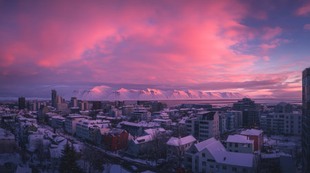 Panoramic shot of Reykjavik skyline at sunrise, with pastel-colored buildings and snow-capped mountains in the distance. No people included.の素材