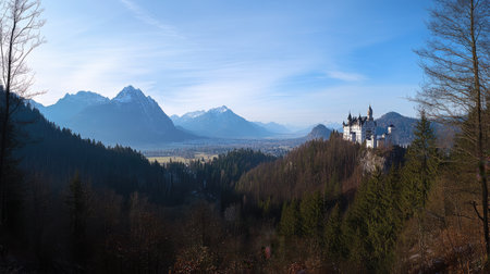 Panoramic view of Neuschwanstein Castle from a distance, showcasing its grandeur against the backdrop of the majestic Alps. No people included.の素材