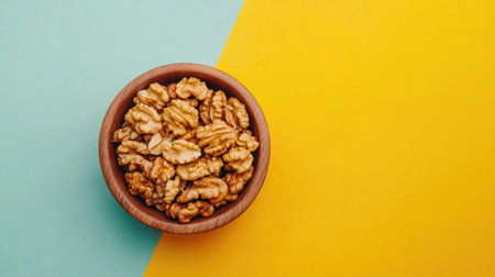 A top view of walnut kernel halves in a wooden bowl on a vibrant backdrop, emphasizing the health benefits of walnuts as superfoods, with ample copy spaceの素材