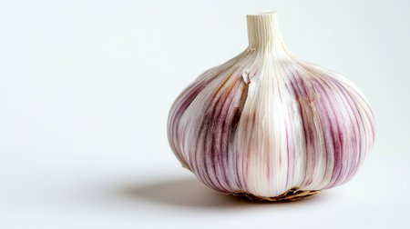 Isolated close-up of a single garlic clove, emphasizing its fine layers and earthy tones against a plain white surfaceの素材