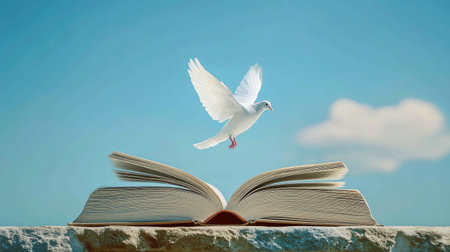 An open book lying on a table with a serene white dove rising from the pages, against a clear blue sky.の素材