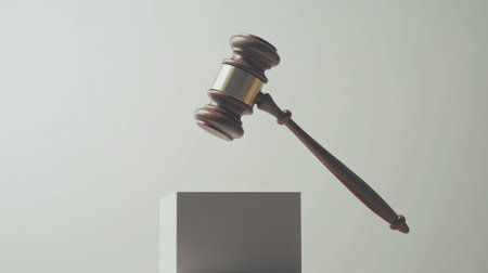 A striking image of a wooden gavel gracefully suspended above a minimalist pedestal, representing justice and authority in a modern legal context. Perfect for legal themes.の素材