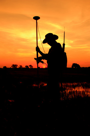 Silhouette of Surveyor worker make data collection with GPS surveying in  field,の写真素材