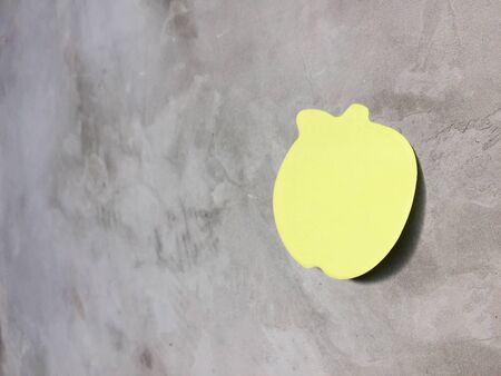Green note paper on gray wall.