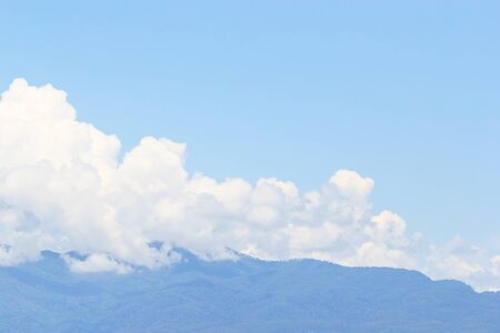 Soft white clouds against blue sky and mountain backgroundの写真素材