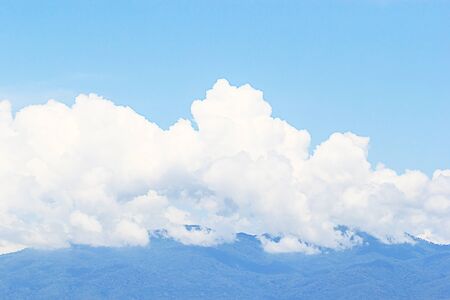 Soft white clouds against blue sky and mountain backgroundの写真素材