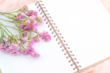 White open notebook and purple flower on pink fabric, soft focus with orange light vintage style.の写真素材
