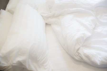 White pillow on the bed with blanket, bedding sheet and shadow soft focus.の写真素材