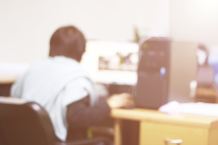 Blur of behind the woman is working on a computer in the office, Orange color tone.の写真素材