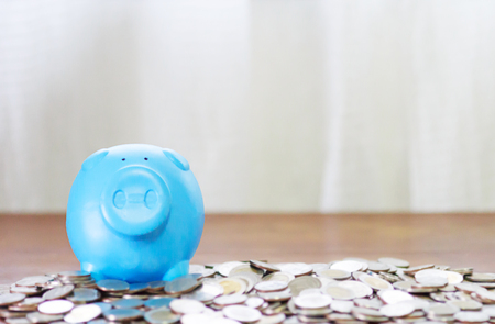Blue piggy bank on top of coins money for savings concept and copy space.の写真素材